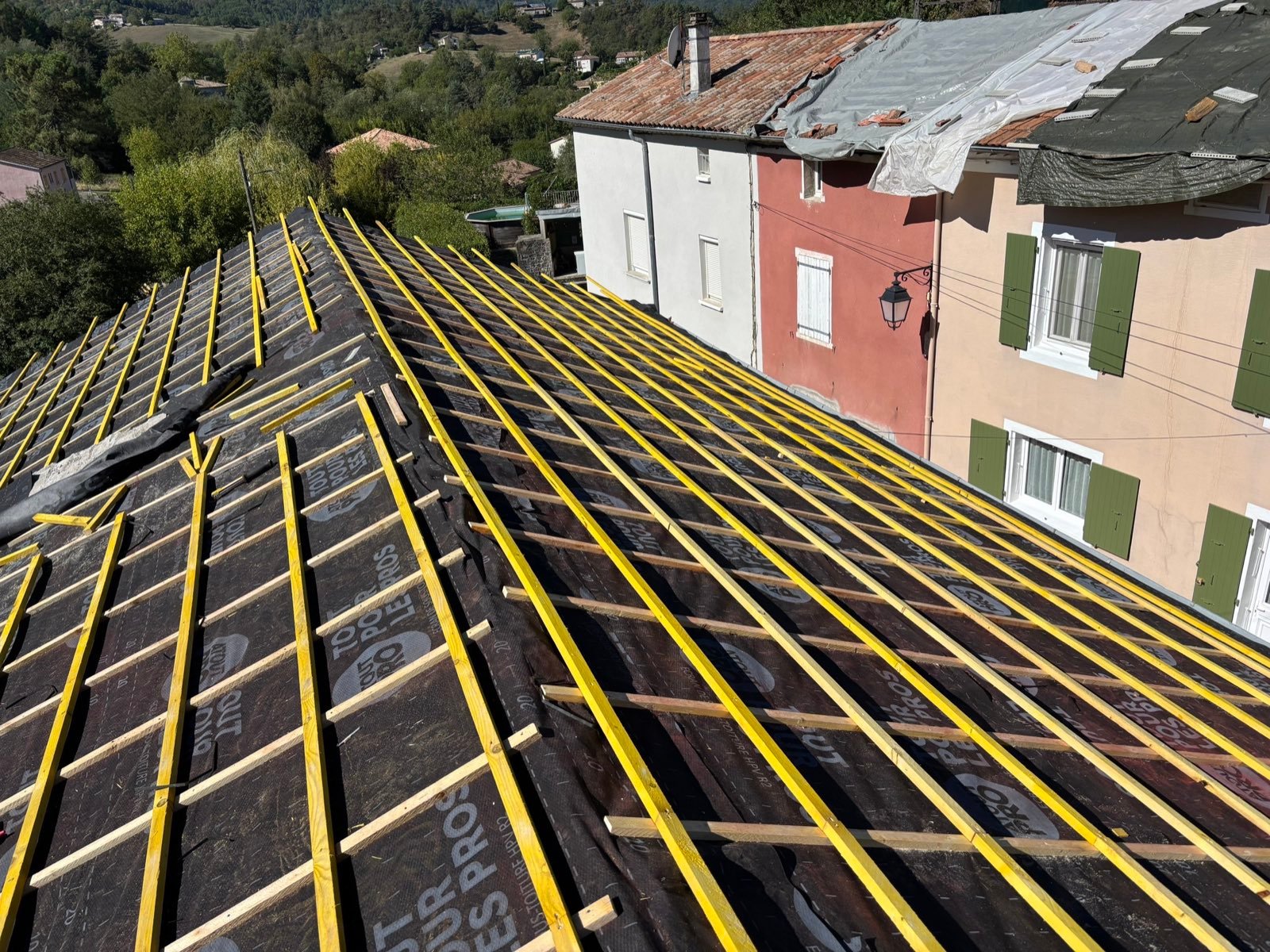 Toiture en cours de rénovation, bâchée, vue par drone au-dessus d'un village de la Drôme